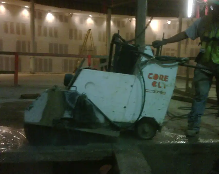 A walk-behind slab saw working an indoor floor, operator on the control bar