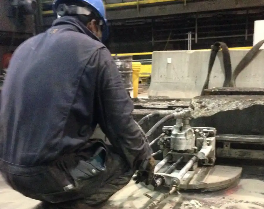 A technician setting a wall-saw track against broken slab inside an industrial plant