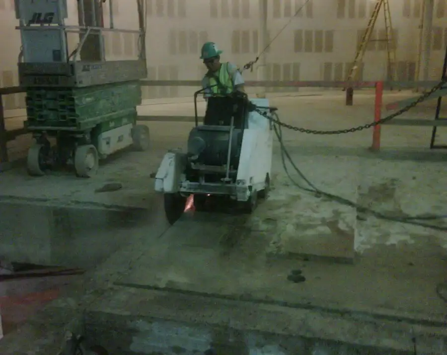 A walk-behind slab saw working an indoor floor in low light