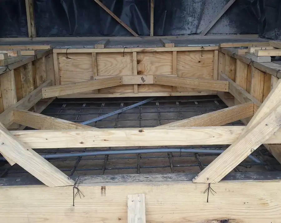 Timber formwork and a rebar mat set over a pit, ready for concrete