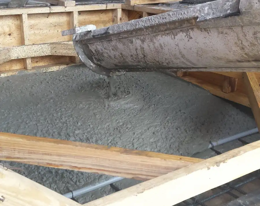 Concrete pouring down a chute into formwork on a fresh slab