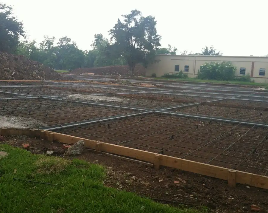 A wide rebar mat and form boards laid across a prepared pad